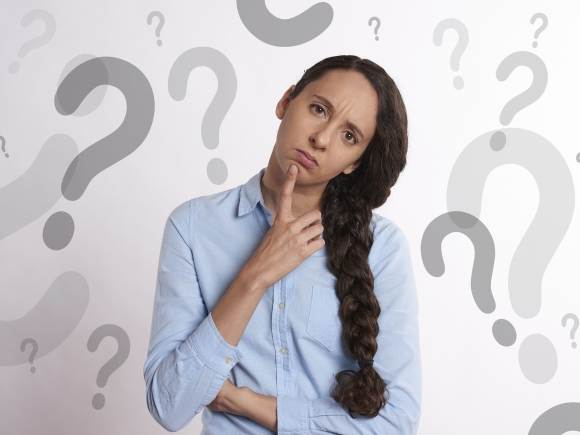 Une femme qui se pose des questions, avec un doigt posé sur le menton.